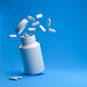 White,pills,from,plastic,medicine,bottle,on,blue,background,with